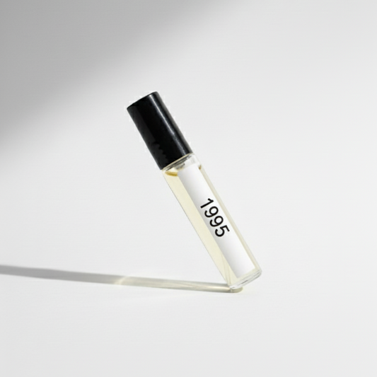 Small Perfume glass bottle with black cap labeled '1995' on a white background