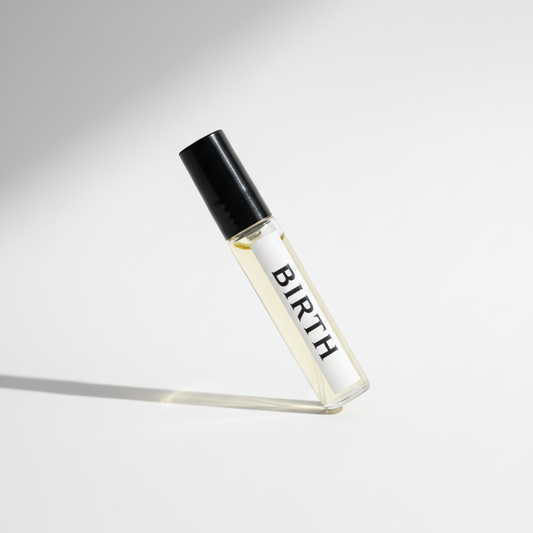 Small glass perfume tester bottle labelled 'BIRTH' with a black cap on a white background